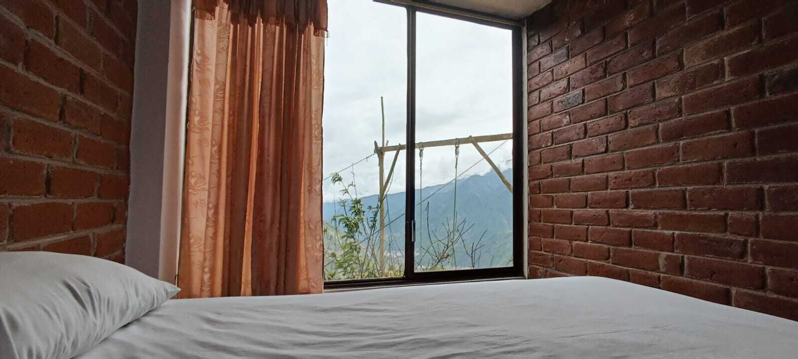 Ein Zimmer mit einem großen Fenster, einem Bett und einer Ziegelwand.
