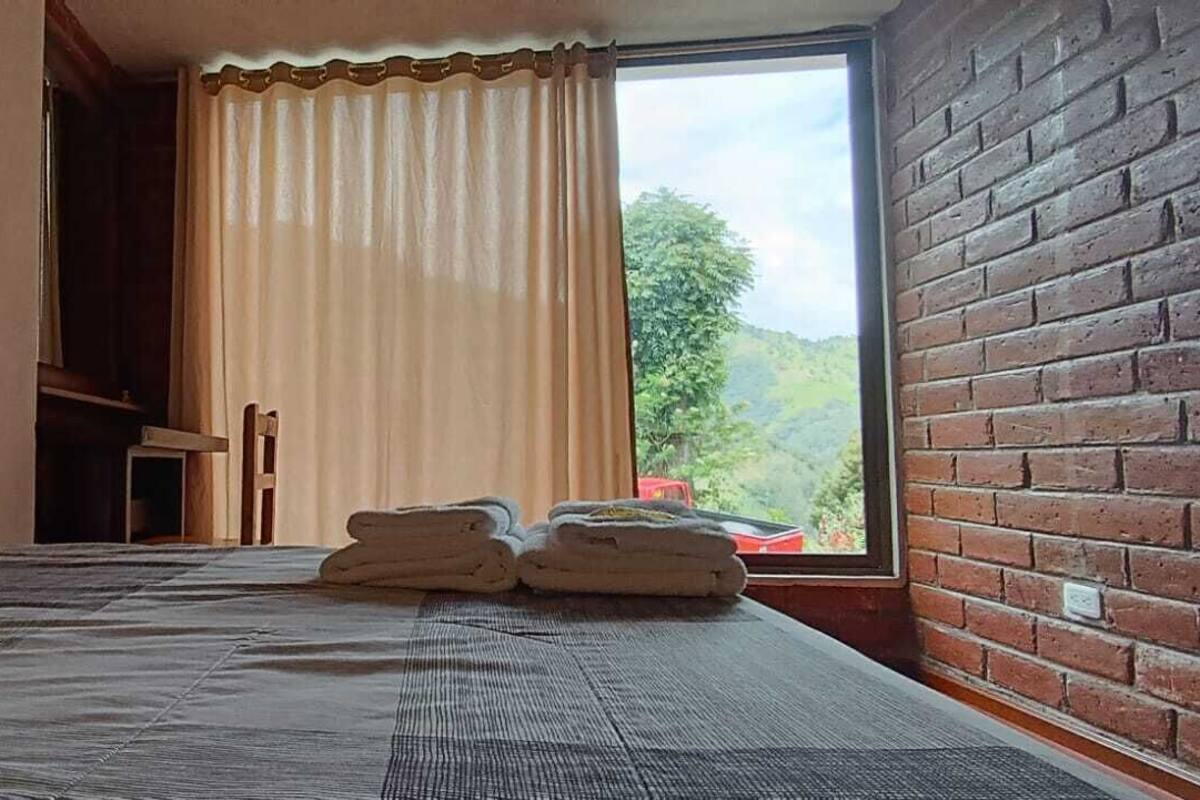 Una habitación con cama, ventana con cortinas y vistas al exterior.