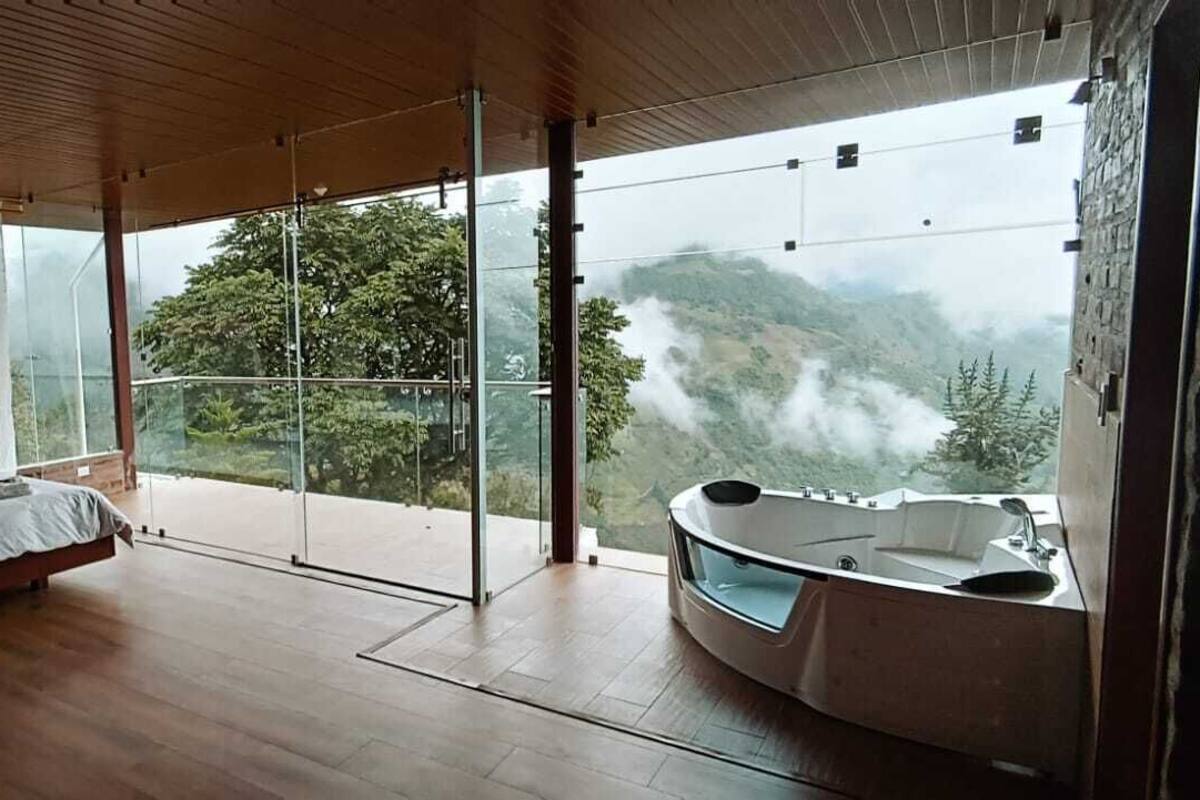 Un dormitorio con una cama grande, un balcón acristalado y un jacuzzi.