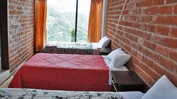 Una habitación con una cama, una mesita de noche y un ventanal con cortinas.