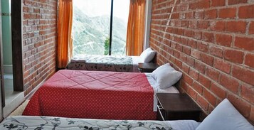 Una habitación con una cama, una mesita de noche y un ventanal con cortinas.