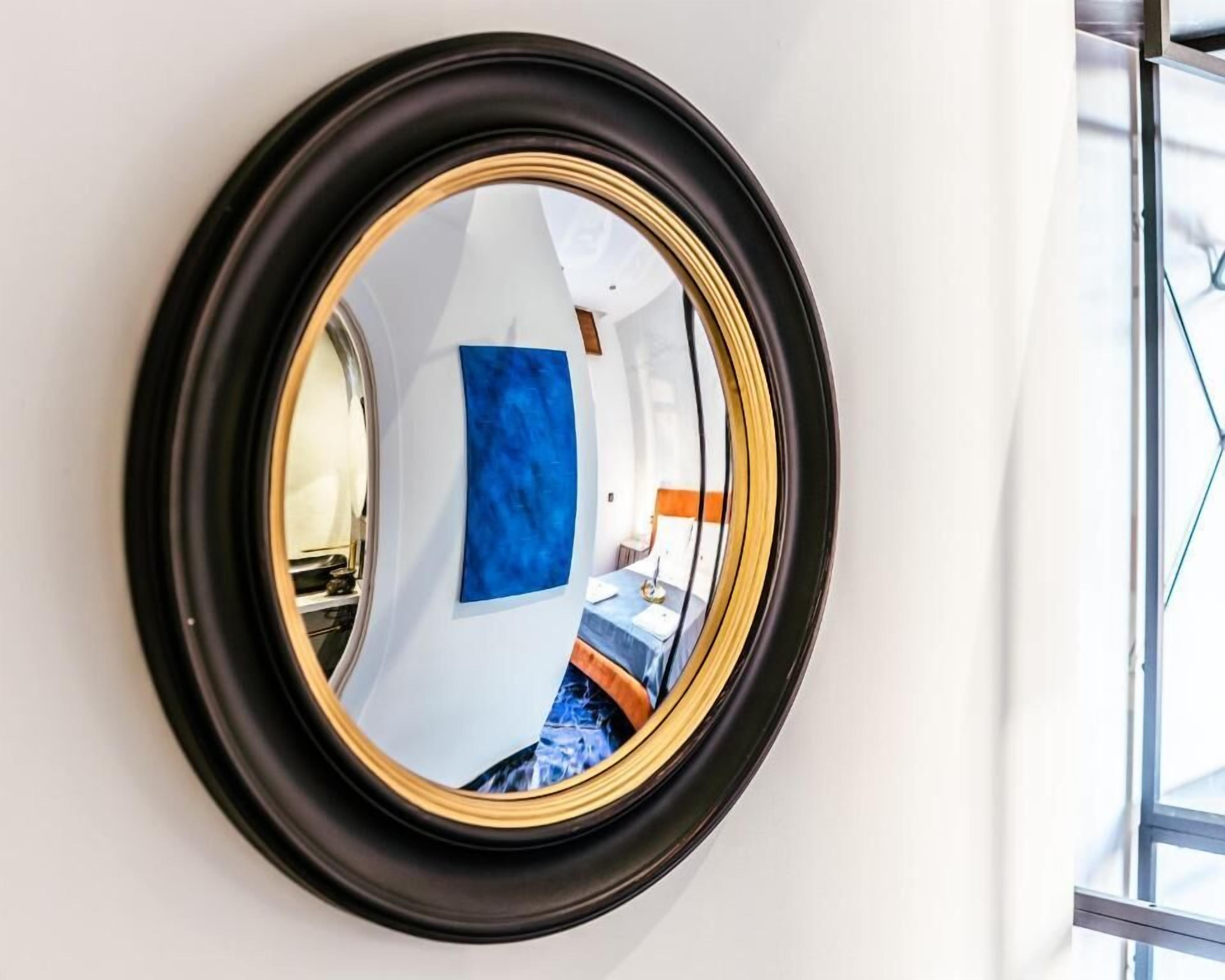 A round mirror with a black frame on a white wall.