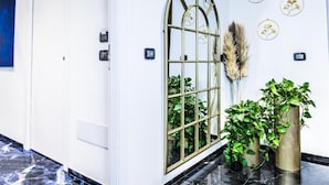 Un couloir doté d’un sol en marbre, d’une fenêtre décorative en métal et de plantes en pot.