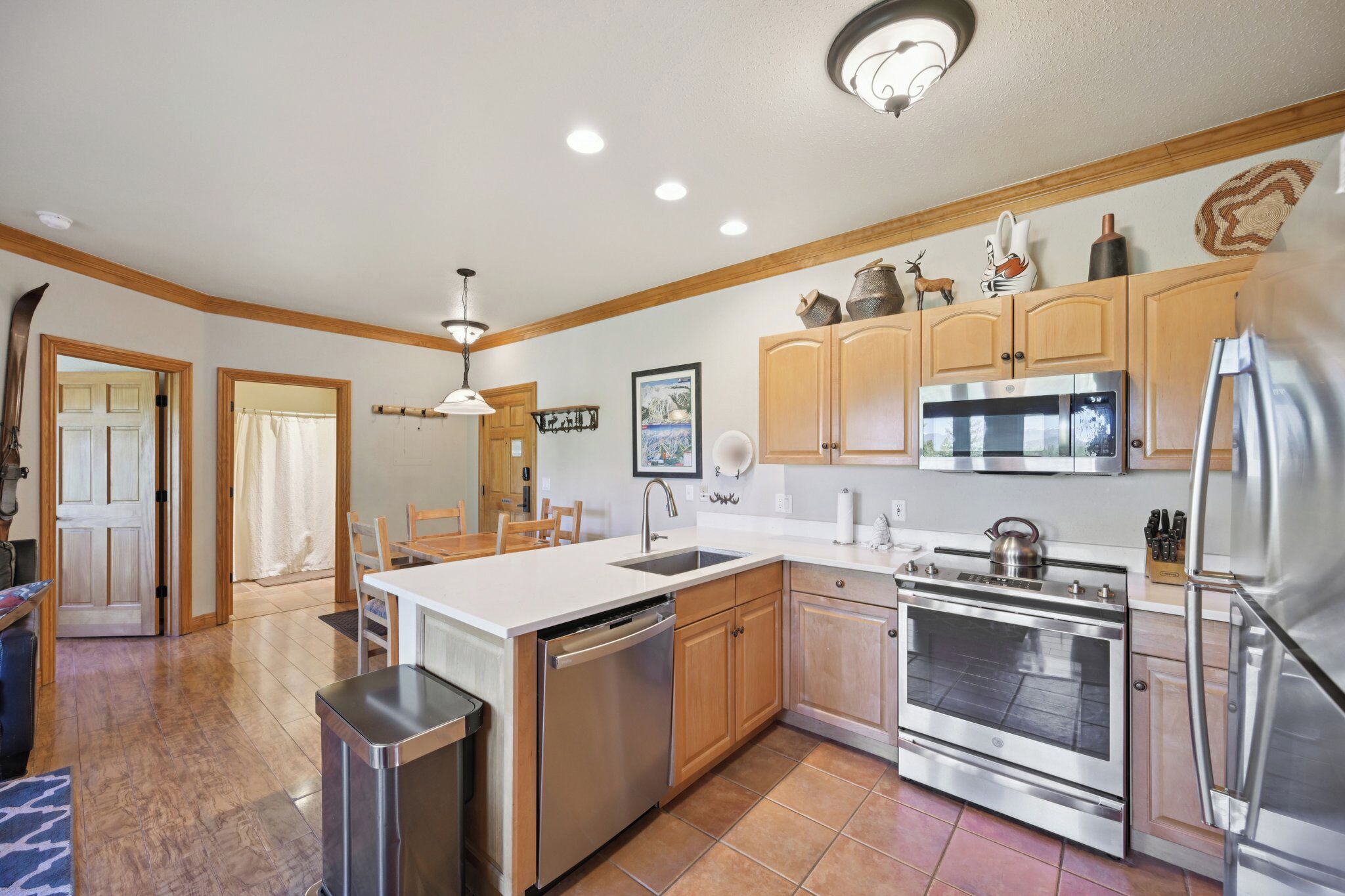 A modern kitchen with wooden cabinets, stainless steel appliances, and a tiled floor.