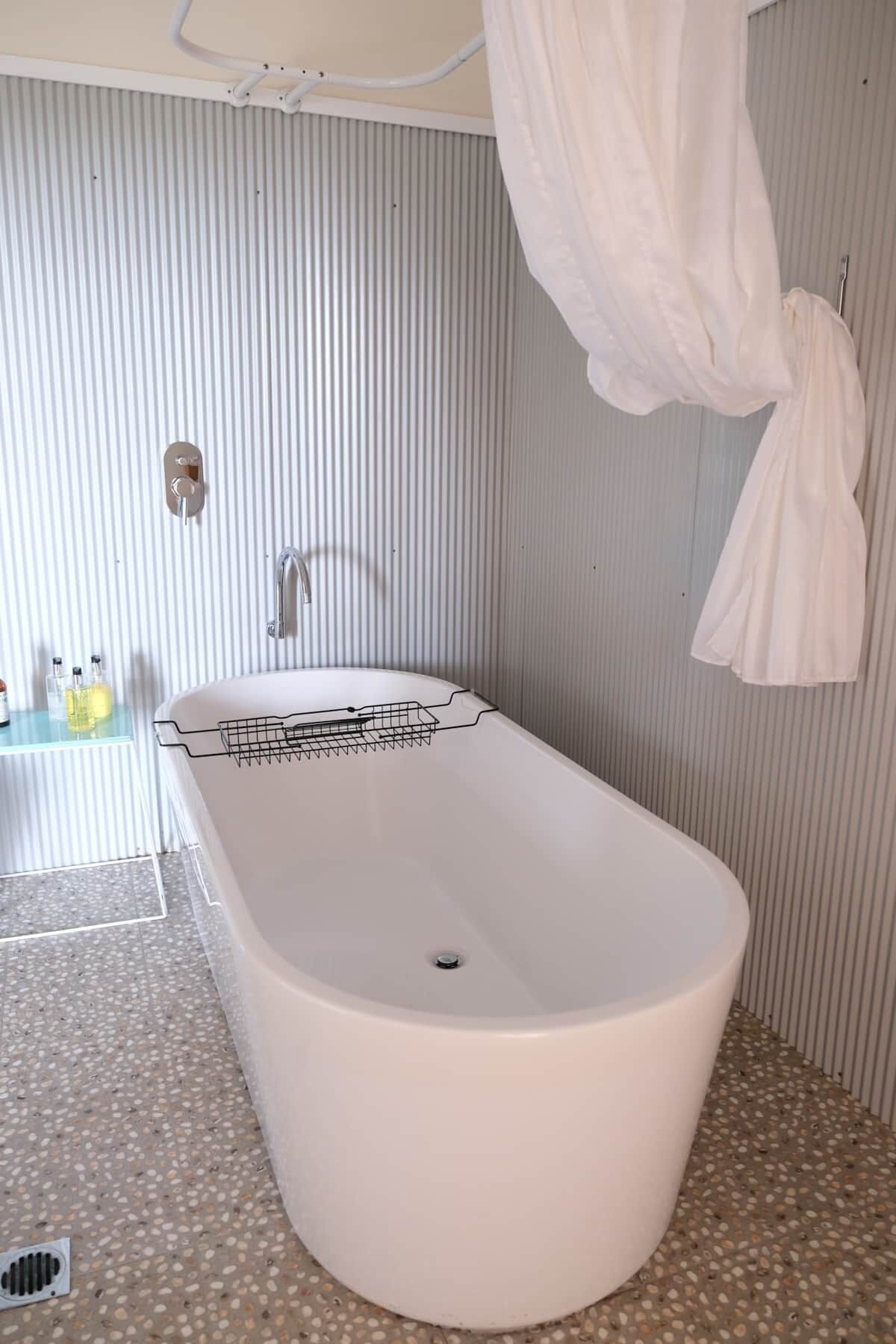 A bathroom with a freestanding bathtub, a towel rack, and a shower curtain.