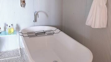 A bathroom with a freestanding bathtub, a towel rack, and a shower curtain.