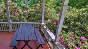 A wooden picnic table with a white railing and pink flowers in the background. - Rustic Log with Pool Game room Amazing koi pound just mins from Hunter Mountain (Elka Park)