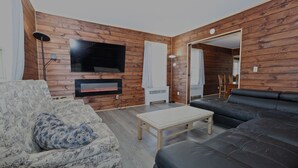 A living room with a sofa, a patterned armchair, a TV, and a fireplace. - Rustic Log with Pool Game room Amazing koi pound just mins from Hunter Mountain (Elka Park)