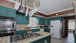 A modern kitchen with teal cabinets, stainless steel appliances, and a tiled backsplash. - Rustic Log with Pool Game room Amazing koi pound just mins from Hunter Mountain (Elka Park)