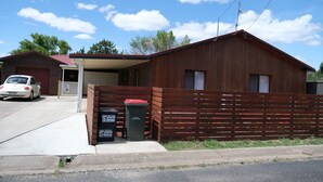Un bâtiment d’un seul étage, doté d’un toit en pente, d’une clôture en bois et d’une voiture garée devant.