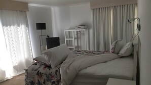 Ein Hotelzimmer mit einem Bett, einem Nachttisch, einem Kleiderschrank, einer Schreibtischlampe und einer Pendelleuchte.