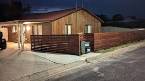 Ein zweigeschossiges Gebäude mit Holzfassade und Metall-Dach. Eine Auffahrt führt zum Eingang, und ein Motorrad steht davor geparkt.