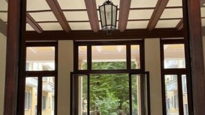 A corridor with a polished marble floor, wooden door frames, and a hanging light fixture.