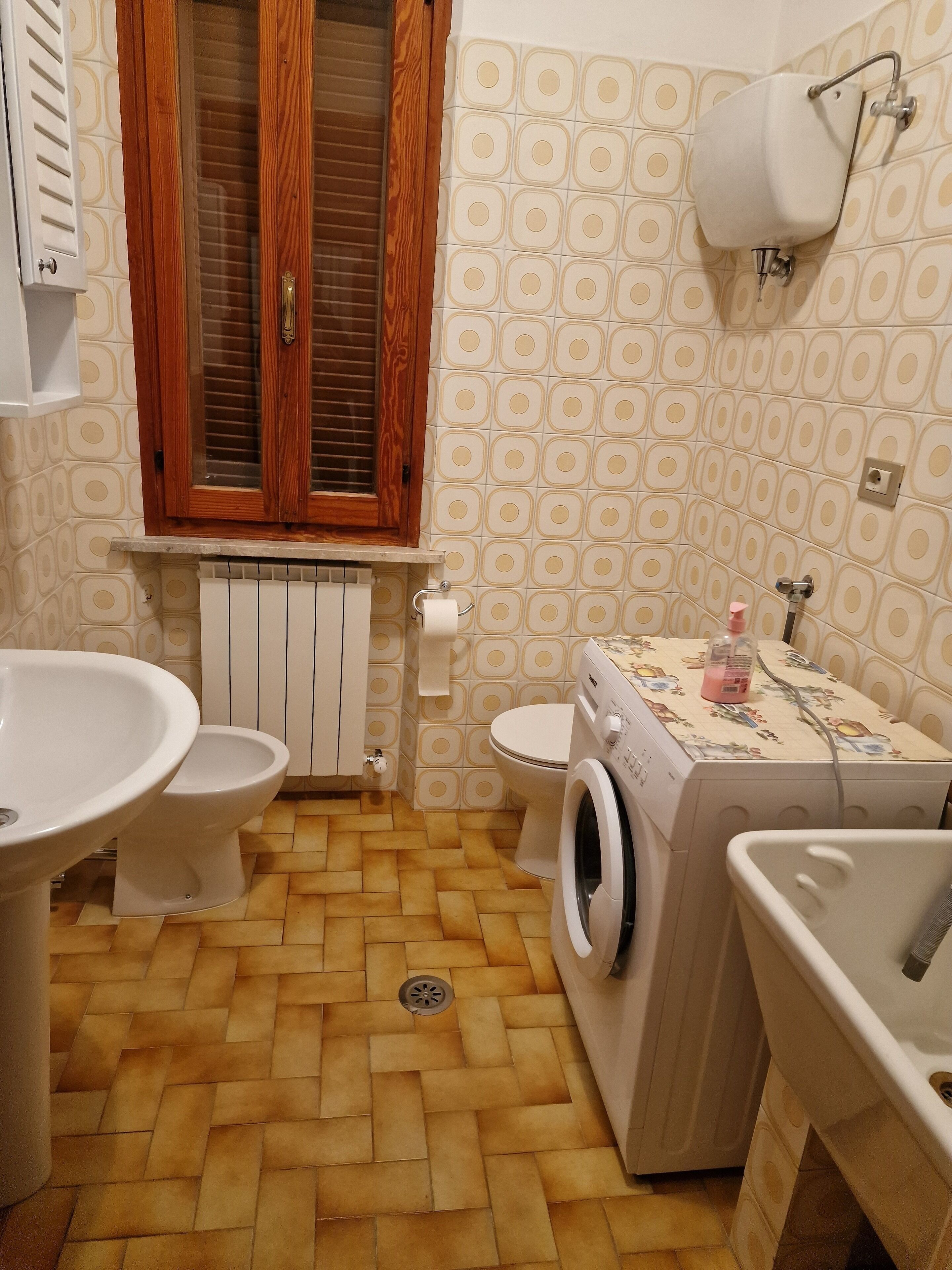 A compact bathroom with a toilet, bidet, washing machine, and sink.