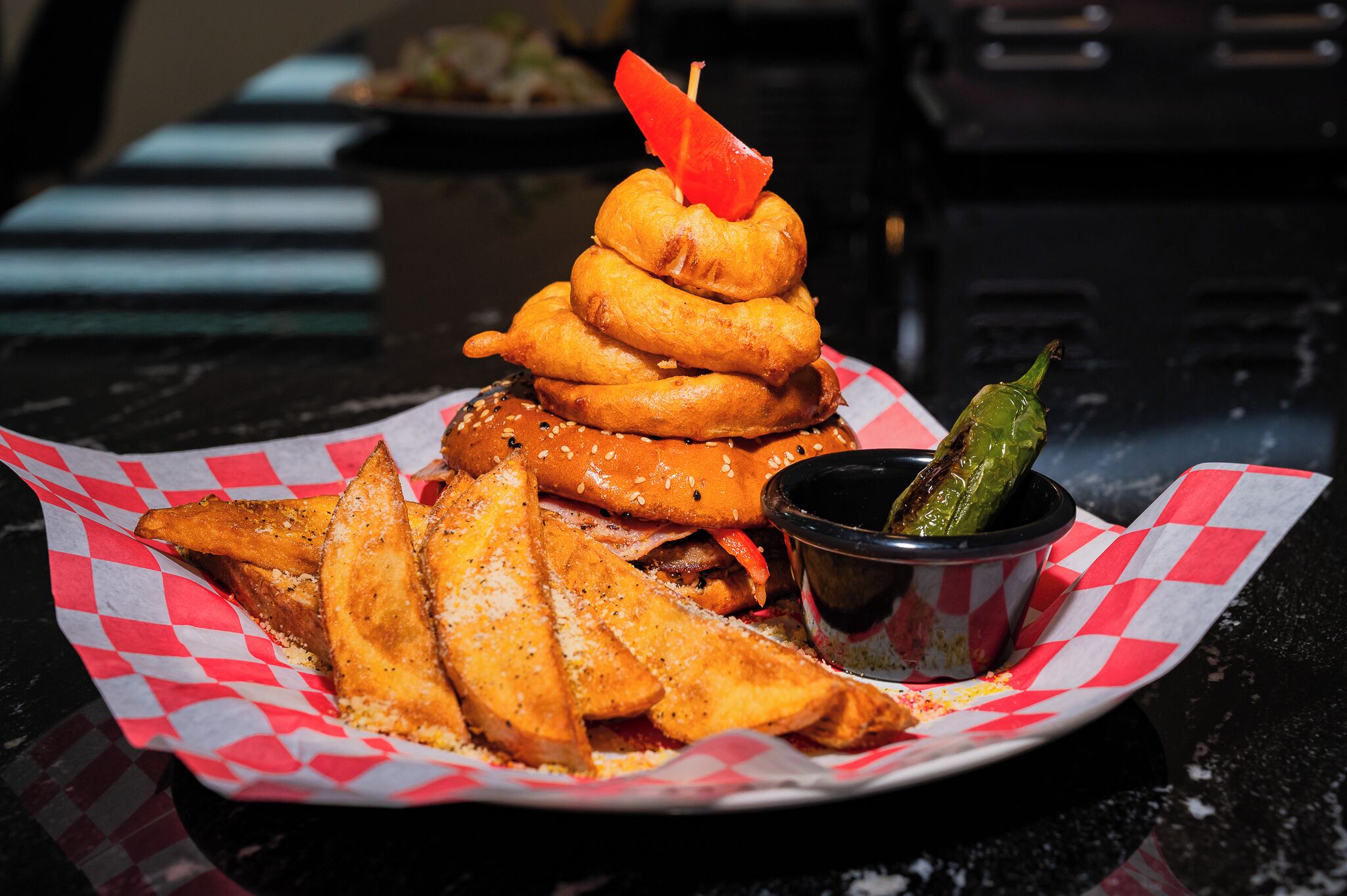 A meal consisting of a burger, onion rings, fries, and a pickle.