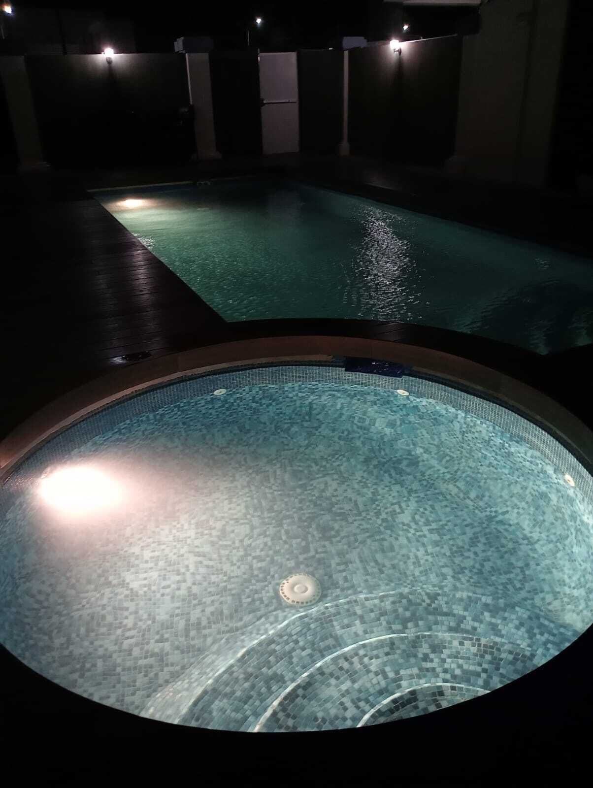 Een zwembadgedeelte met betegelde vloer en een rond bubbelbad.