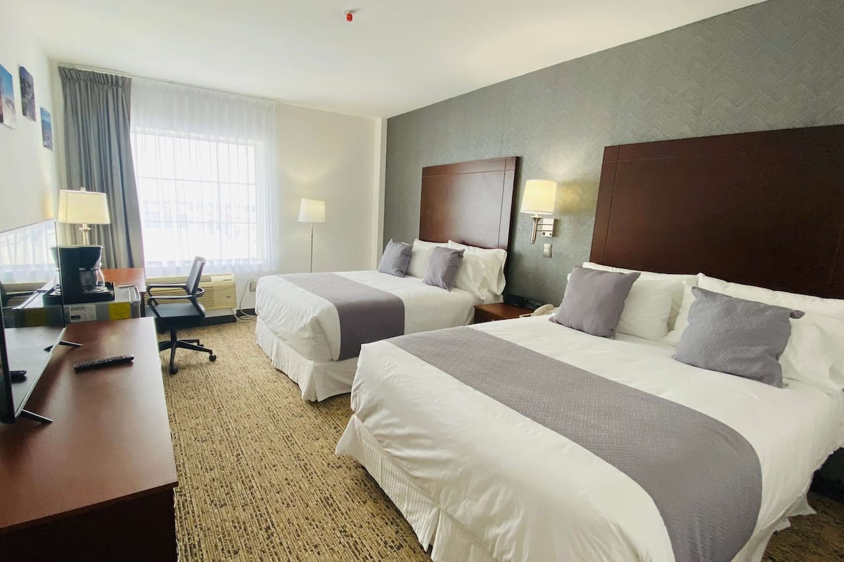 Una habitación de hotel con dos camas, un escritorio y una silla.