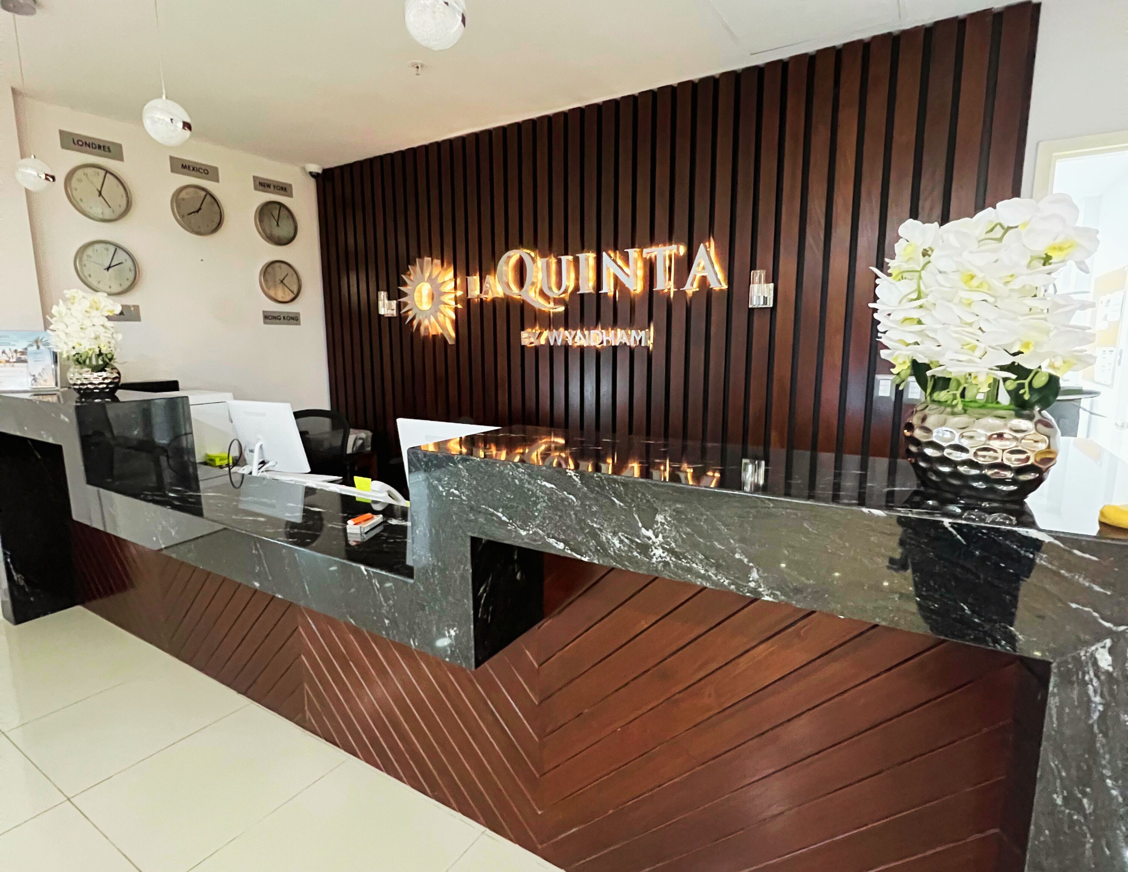 A hotel reception desk with a modern design, featuring a wooden panel wall and a glass counter.