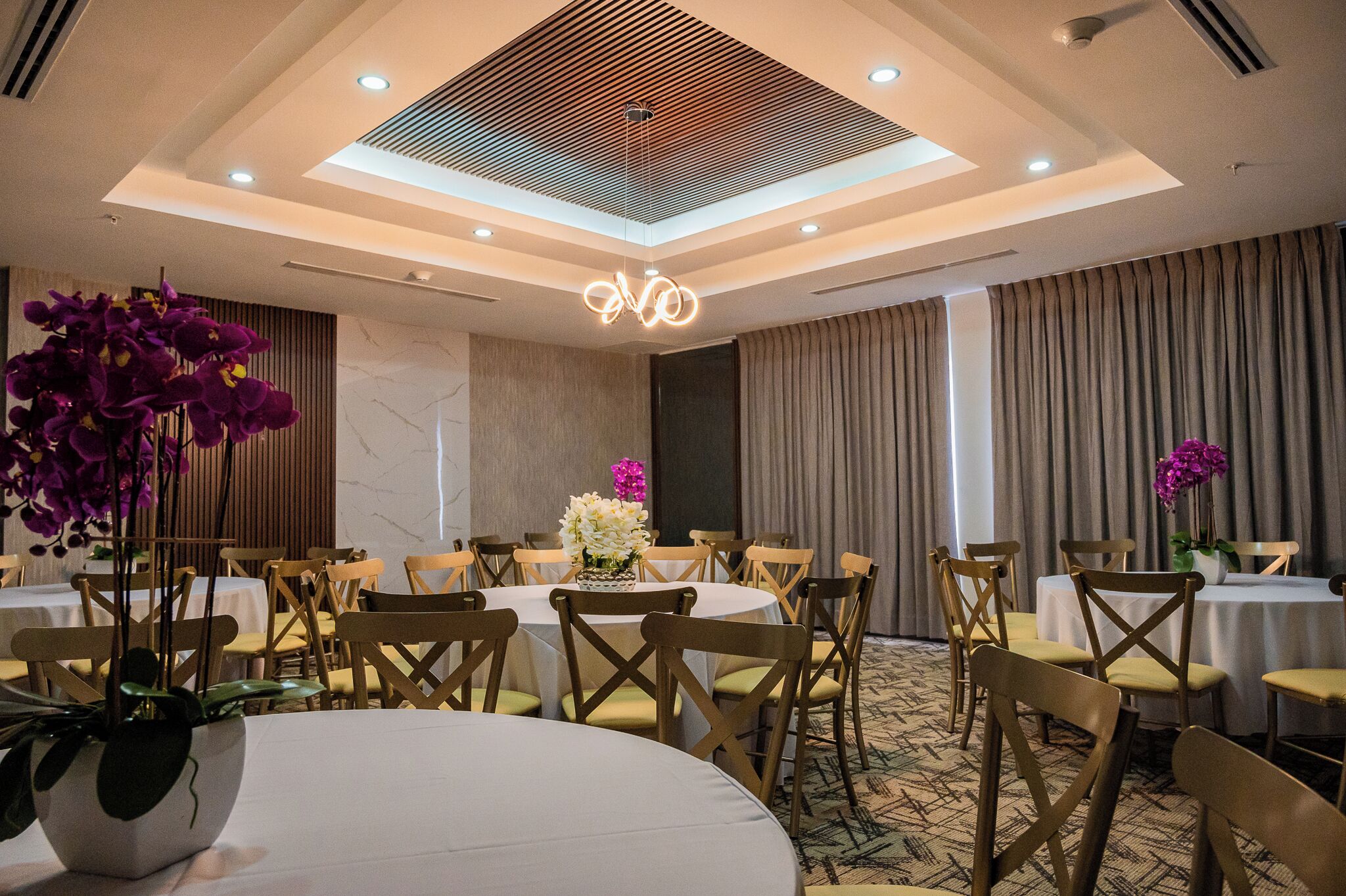 A conference room with round tables, wooden chairs, and floral centerpieces.