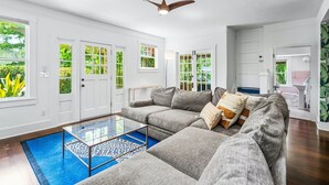 A spacious living room with a large sectional sofa, a glass coffee table, and a ceiling fan.