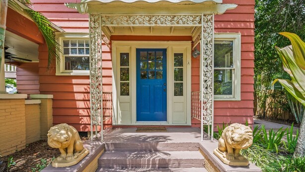 A house with a blue front door, two lion statues, and a decorative porch.
