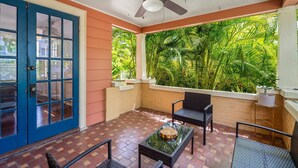 A room with a blue door, a ceiling fan, and a view of lush greenery.