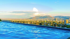 A swimming pool with a view of a cityscape and mountains in the background. - Altos Tower Apartamento de 3 habitaciones (San Salvador)