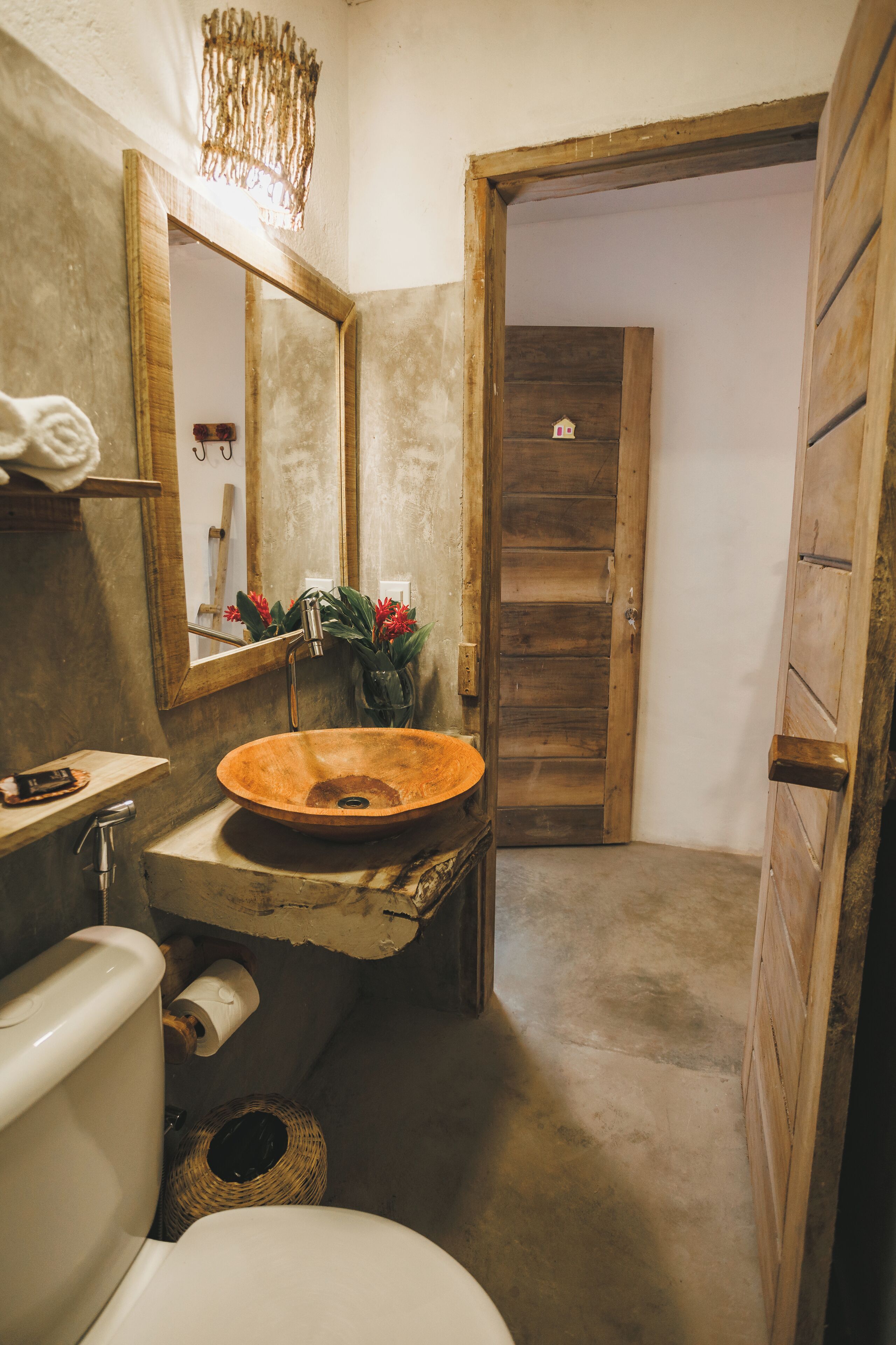 A rustic bathroom with a wooden sink, a mirror, and a toilet.