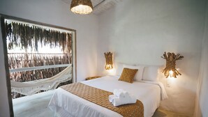 A bedroom with a large bed, a hammock outside the window, and two wall-mounted lamps. - Pousada Villa Cacau (Porto Seguro)