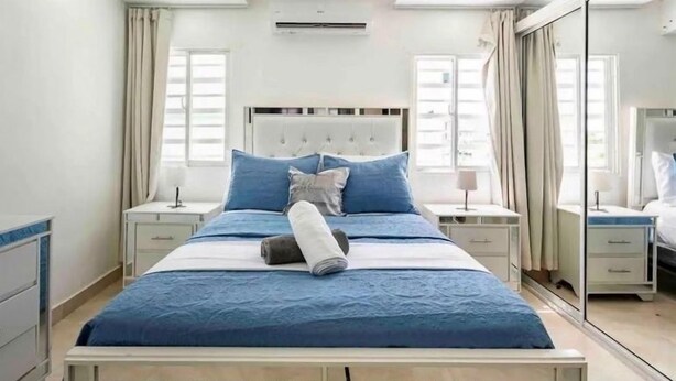 A bedroom with a bed, nightstands, a mirror, and a window.
