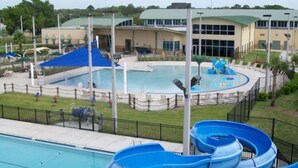 A swimming pool with a water slide and a building in the background. - Charming 1-Bedroom Oasis in the Heart of Downtown (New Port Richey)