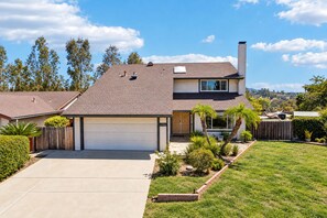 A two-story house with a garage, a chimney, and a well-maintained lawn. - Spacious Family Retreat · Views · Hot Tub · BBQ · Sleeps 6-10 (San Diego)