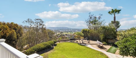 Un césped cuidado con un sendero de piedra, una hamaca y vistas a un horizonte urbano distante.
