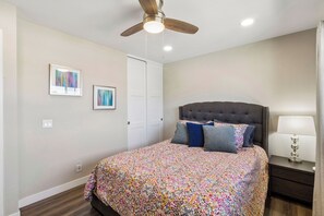 A bedroom with a bed, a ceiling fan, a nightstand with a lamp, and two framed artworks on the wall. - Spacious Family Retreat · Views · Hot Tub · BBQ · Sleeps 6-10 (San Diego)