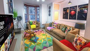 Un saló amb un sofà, una taula de centre, una catifes acolorida i una televisió.
