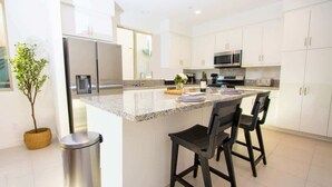 A modern kitchen with white cabinets, stainless steel appliances, and a granite countertop.