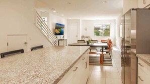 A modern kitchen with a granite countertop, stainless steel appliances, and a dining area with a table and chairs.