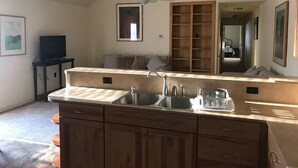 A kitchen with a central island, wooden cabinets, a built-in oven, and a ceiling fan. - The Sunflower Cottage (San Marcos)