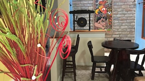 A dining area with a rustic brick wall, a mural, and a table with chairs. - Apartahotel Tierras Amazonicas (Leticia)
