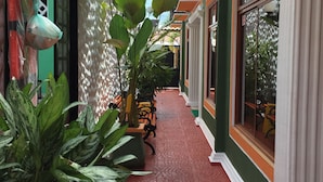A narrow corridor with red brick flooring, green and white walls, and large potted plants. - Apartahotel Tierras Amazonicas (Leticia)