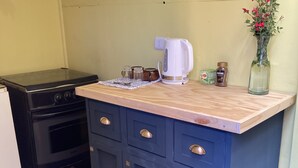 Een kleine keuken met een fornuis, een koffiezetapparaat en een klein aanrecht.