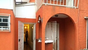 Een smalle gang met een witte deur en een klein balkon met een witte balustrade.