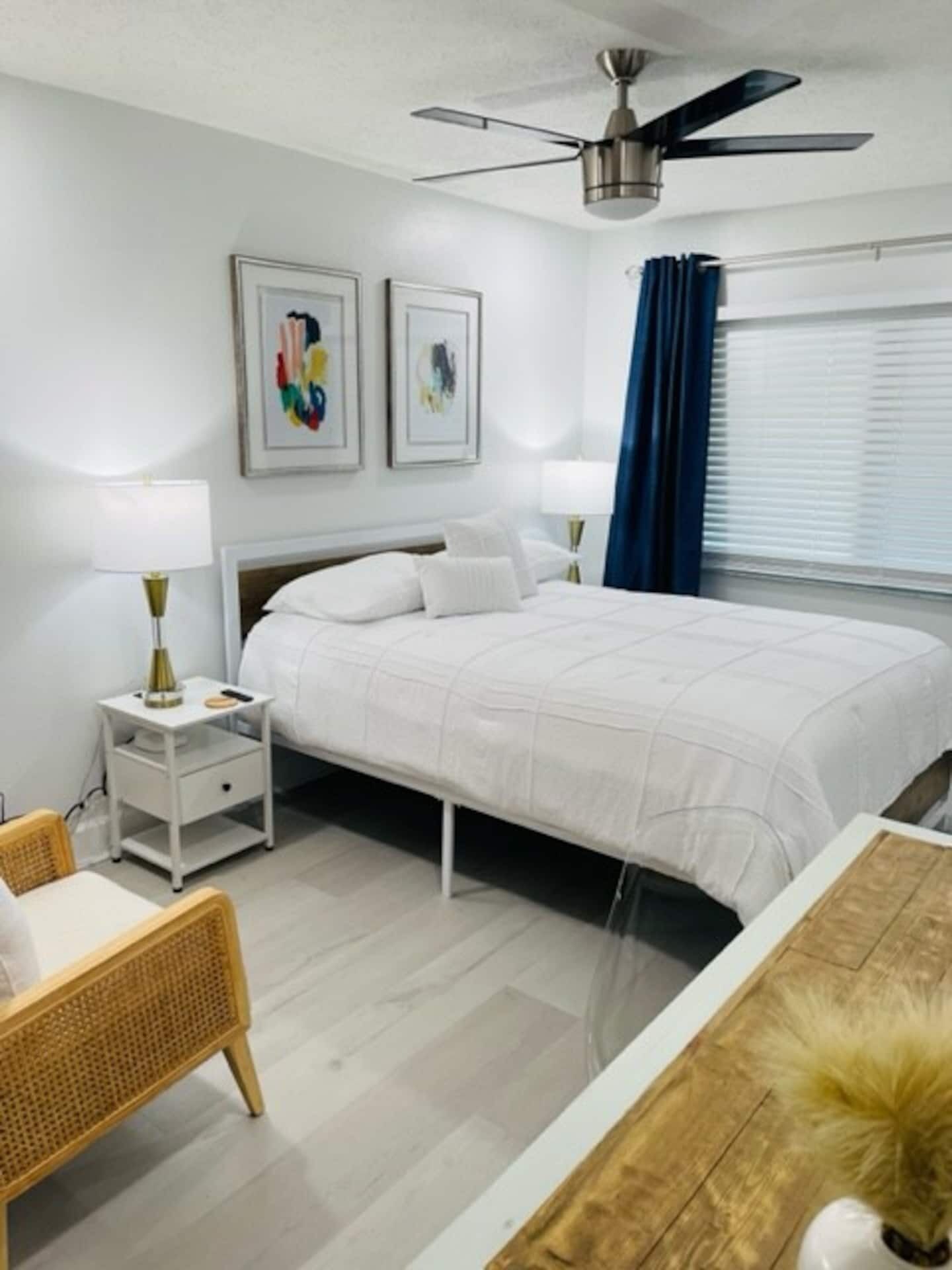 Una camera da letto con un letto, comodini, una ventola a soffitto e opere d'arte alle pareti.