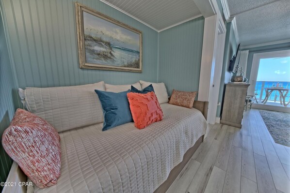 Ein Schlafzimmer mit einem großen Bett, einem Strandbild und Meerblick durch ein Fenster.
