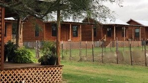 Une cabane en bois avec une cour clôturée et un chien.