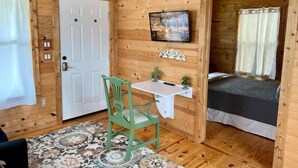 Une chambre dans un chalet en bois, comprenant un lit, un bureau, une chaise et un téléviseur.