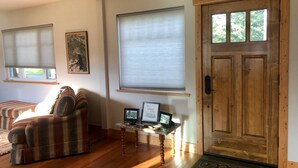A cozy living room with a plaid sofa, a wooden door, and a small table with framed pictures.