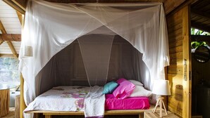 A wooden bed with a canopy, pillows, and a bedside lamp. - Villa Tiki a harmonious composition with a charming bungalow and private pool (Le Moule)