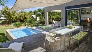 A modern outdoor patio with a pool, seating, and a table. - Villa Tiki a harmonious composition with a charming bungalow and private pool (Le Moule)