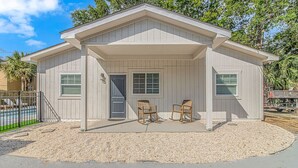 Une maison de plain-pied avec un porche couvert, une porte d’entrée et deux fenêtres.